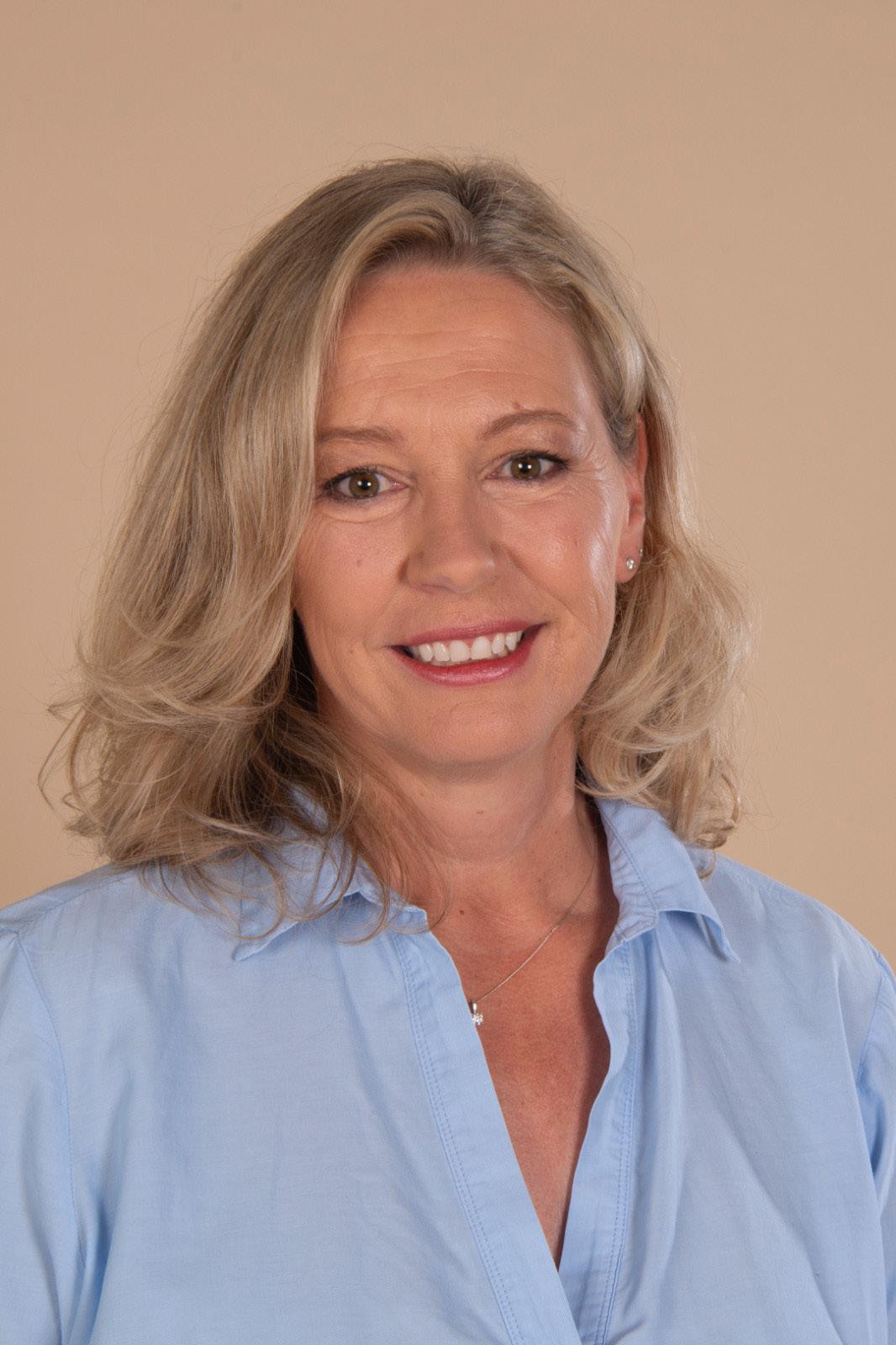 Claudia Brett smiling in a light blue shirt.
